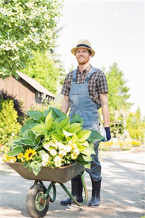 simsearch:693-07912856,k - Full-length of gardener pushing wheelbarrow with plants at garden Stock Photo - Premium Royalty-Free, Code: 693-07912926