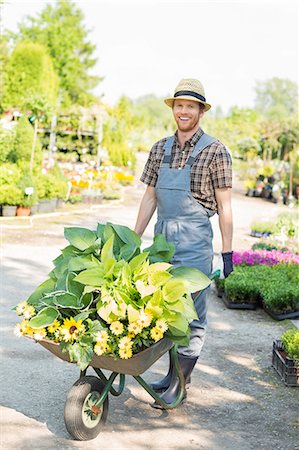 simsearch:693-07912855,k - Full-length portrait of happy gardener pushing wheelbarrow with plants at garden Stock Photo - Premium Royalty-Free, Code: 693-07912927