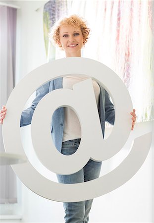 simsearch:693-07912497,k - Portrait of confident businesswoman holding at sign in creative office Foto de stock - Sin royalties Premium, Código: 693-07912949