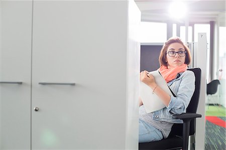 simsearch:693-07912497,k - Businesswoman holding notepad while sitting on chair at creative office Foto de stock - Sin royalties Premium, Código: 693-07913017