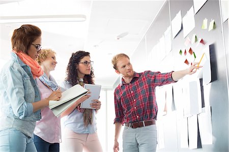 pad of paper - Young businessman explaining document to female colleagues in creative office Stock Photo - Premium Royalty-Free, Code: 693-07913011