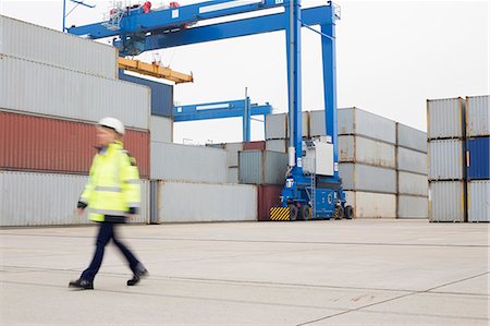 Full-length of female worker walking in shipping yard Foto de stock - Sin royalties Premium, Código: 693-07913091