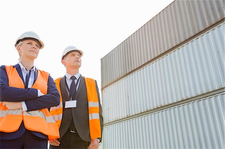 engineer standing with arms crossed - Low angle view of workers standing against cargo containers Photographie de stock - Premium Libres de Droits, Code: 693-07913127