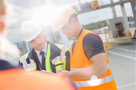 protective clothing - Male workers discussing over clipboard in shipping yard Stock Photo - Premium Royalty-Free, Code: 693-07913165