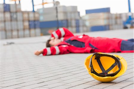 polen - Yellow hardhat at shipyard with depressed male worker lying in shipping yard Foto de stock - Sin royalties Premium, Código: 693-07913181