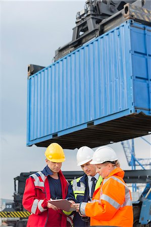 Workers discussing over clipboard in shipping yard Fotografie stock - Premium Royalty-Free, Codice: 693-07913183