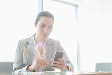 simsearch:695-05767911,k - Young businesswoman using cell phone in office Stock Photo - Premium Royalty-Free, Code: 693-07913201
