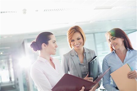 documento - Businesswomen with file folders discussing in office Foto de stock - Sin royalties Premium, Código: 693-07913229