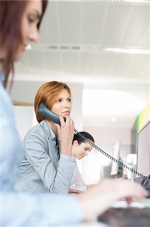 simsearch:693-07913227,k - Young businesswoman using landline phone in office Foto de stock - Royalty Free Premium, Número: 693-07913223