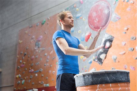 simsearch:632-06317753,k - Low angle view of confident man dusting powder by climbing wall in crossfit gym Photographie de stock - Premium Libres de Droits, Code: 693-08126915