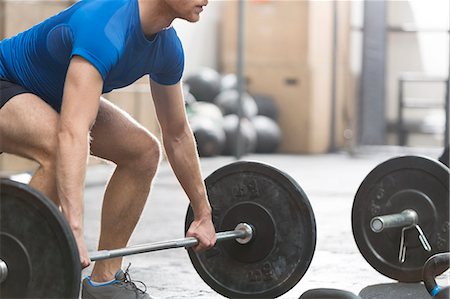 Low section of dedicated man lifting barbell in crossfit gym Foto de stock - Sin royalties Premium, Código: 693-08126925