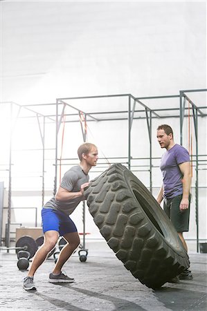 simsearch:693-08126948,k - Man looking at dedicated friend flipping tire in crossfit gym Stock Photo - Premium Royalty-Free, Code: 693-08126932