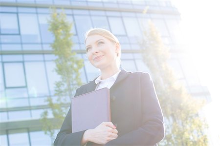 Low angle view of thoughtful businesswoman holding folder on sunny day Stock Photo - Premium Royalty-Free, Code: 693-08126979