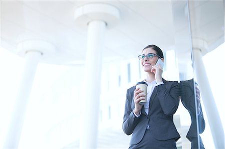 simsearch:693-06435813,k - Businesswoman using cell phone while holding disposable cup outdoors Foto de stock - Sin royalties Premium, Código: 693-08126999