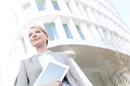 Low angle view of confident businesswoman holding digital tablet outside office building Foto de stock - Sin royalties Premium, Código: 693-08127014