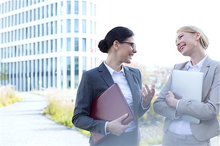 simsearch:693-08127175,k - Cheerful businesswomen conversing while holding folder and laptop outside office building Fotografie stock - Premium Royalty-Free, Codice: 693-08127011