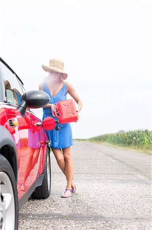 filling (putting) - Full-length of woman refueling car on country road against clear sky Stock Photo - Premium Royalty-Free, Code: 693-08127131