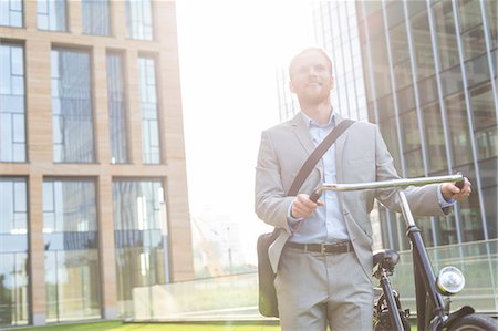 simsearch:693-08127175,k - Thoughtful businessman standing with bicycle outside building Fotografie stock - Premium Royalty-Free, Codice: 693-08127179