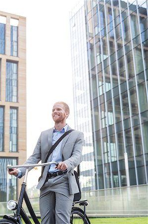 simsearch:693-06403489,k - Happy businessman with bicycle standing outside office building Stock Photo - Premium Royalty-Free, Code: 693-08127171