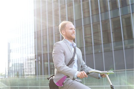 simsearch:693-06403501,k - Businessman riding bicycle outside office building Stock Photo - Premium Royalty-Free, Code: 693-08127181