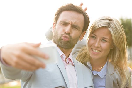 simsearch:693-06403498,k - Playful business couple taking selfie outdoors on sunny day Stock Photo - Premium Royalty-Free, Code: 693-08127194