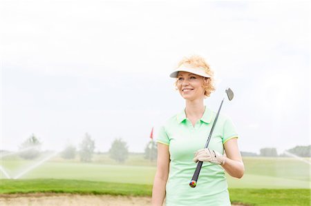 simsearch:693-08127270,k - Happy middle-aged woman looking away while holding golf club Foto de stock - Sin royalties Premium, Código: 693-08127226