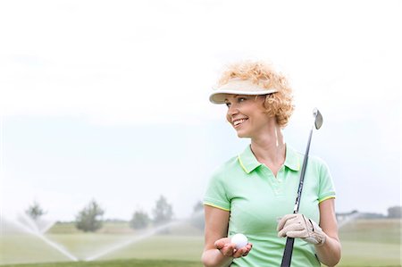 simsearch:693-08127270,k - Happy middle-aged woman looking away while holding golf club and ball Foto de stock - Sin royalties Premium, Código: 693-08127228