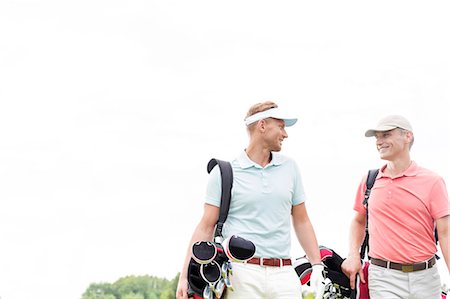 Happy male golfers communicating against clear sky Foto de stock - Sin royalties Premium, Código: 693-08127222