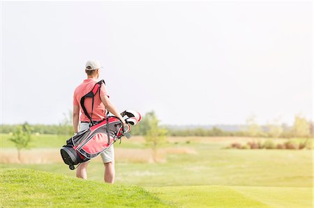simsearch:649-08422474,k - Rear view of man carrying golf club bag while walking at course Stock Photo - Premium Royalty-Free, Code: 693-08127259