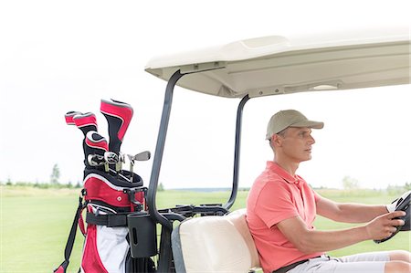 driver (vehicle, male) - Middle-aged man driving golf cart at course Foto de stock - Sin royalties Premium, Código: 693-08127251