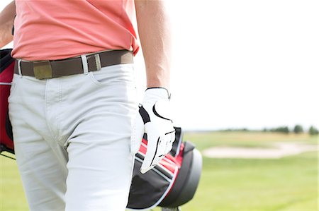 Midsection of man carrying golf club bag while walking at course Stock Photo - Premium Royalty-Free, Code: 693-08127264