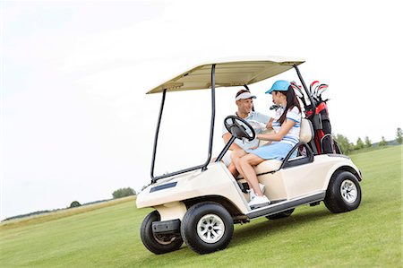 simsearch:693-06668077,k - Couple looking at each other while sitting in golf cart against clear sky Fotografie stock - Premium Royalty-Free, Codice: 693-08127269