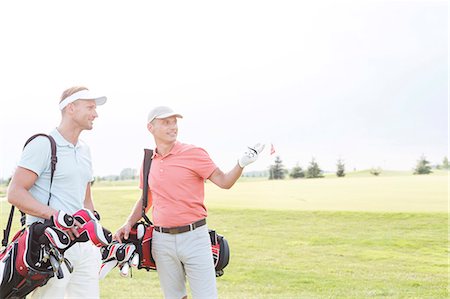 Man showing something to friend at golf course against clear sky Stock Photo - Premium Royalty-Free, Code: 693-08127278