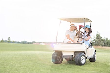 simsearch:693-08126937,k - Couple looking at each other while sitting in golf cart against clear sky Stock Photo - Premium Royalty-Free, Code: 693-08127270