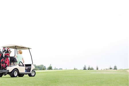 simsearch:693-06668077,k - Couple sitting in golf cart against clear sky Fotografie stock - Premium Royalty-Free, Codice: 693-08127271