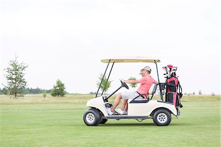 simsearch:693-08127270,k - Side view of couple sitting in golf cart against clear sky Foto de stock - Sin royalties Premium, Código: 693-08127272
