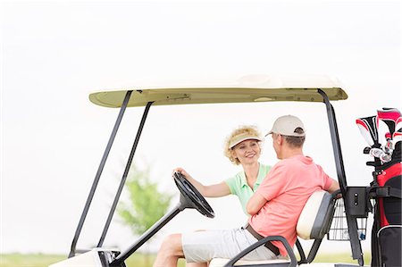 simsearch:693-06668077,k - Happy woman looking at man while sitting in golf cart Fotografie stock - Premium Royalty-Free, Codice: 693-08127273