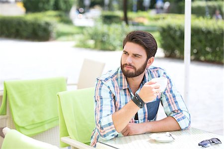 simsearch:693-08127426,k - Thoughtful man holding coffee cup at sidewalk cafe Stock Photo - Premium Royalty-Free, Code: 693-08127403