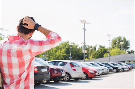 person standing back building street - Rear view of man with hand behind head standing on city street against clear sky Stock Photo - Premium Royalty-Free, Code: 693-08127429