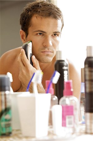 simsearch:693-06019176,k - Reflection of young man in mirror shaving with electric shaver Stock Photo - Premium Royalty-Free, Code: 693-08127551