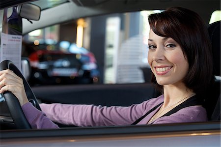 Portrait of young woman sitting in driver's seat at car dealersh Stock Photo - Premium Royalty-Free, Code: 693-08127577