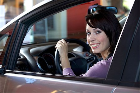 Portrait of young woman sitting in driver's seat at car dealership Stock Photo - Premium Royalty-Free, Code: 693-08127578