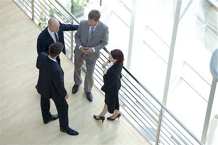 Businessmen and woman standing together by railing conversing Stock Photo - Premium Royalty-Free, Code: 693-08127598