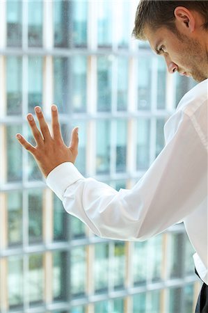 Young caucassian businessman standing against office window Photographie de stock - Premium Libres de Droits, Code: 693-08127603