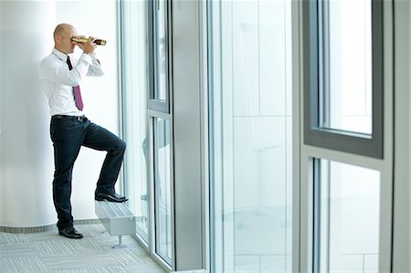 person focusing telescope - caucasian businessman spying using telescope thru office window Stock Photo - Premium Royalty-Free, Code: 693-08127613