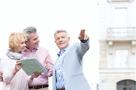 Man showing direction to couple with road map in city Fotografie stock - Premium Royalty-Free, Codice: 693-08127676