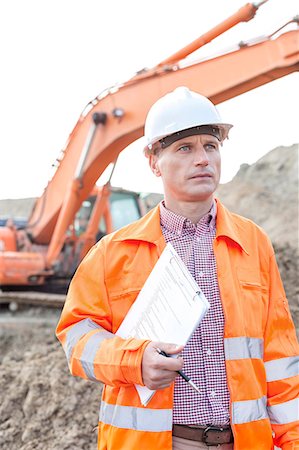 Architect looking away while holding clipboard at construction site Stock Photo - Premium Royalty-Free, Code: 693-08127725