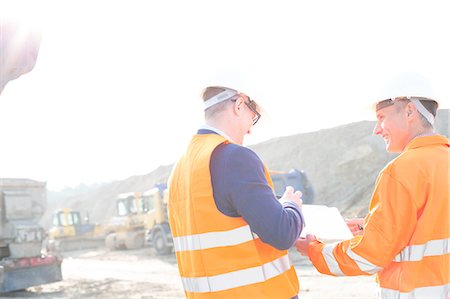 from behind - Happy engineers discussing over clipboard at construction site against clear sky Stock Photo - Premium Royalty-Free, Code: 693-08127738