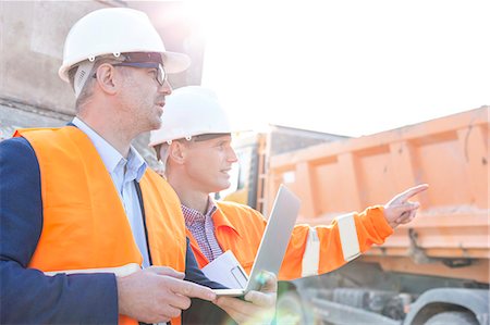 Supervisor showing something to colleague holding laptop at construction site Photographie de stock - Premium Libres de Droits, Code: 693-08127744