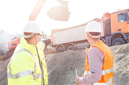 Engineer pointing at vehicles while discussing at construction site Stock Photo - Premium Royalty-Free, Code: 693-08127779